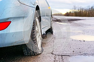 Flat tire of blue car on the road waiting for repair. Car tire leak because of nail pounding