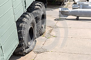 Flat tire of old military heavy truck. General-purpose air bombs on background. Army decay and degradation concept