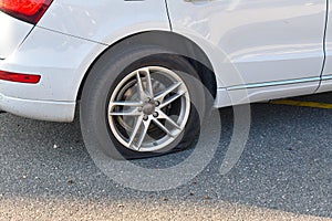 Flat tire on a white car on an asphalt road