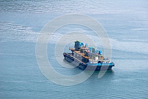 Flat top barge carries structures that seem to be an oil rig