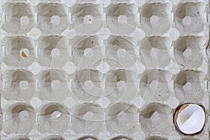 Flat view of a box with broken eggshell brown chicken eggs, background texture pattern