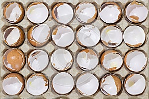 Flat view of a box with broken eggshell brown chicken eggs, background texture pattern