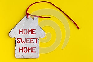 Flat vintage white wooden house with a pipe, a red rope and the inscription home sweet home on a bright yellow background