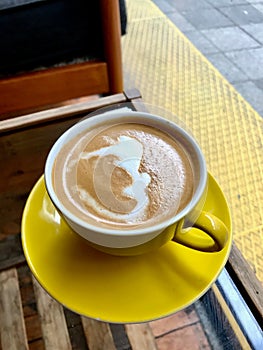 Flat White Coffee with Foamy Milk in Yellow Cup served at Cafe Shop. photo