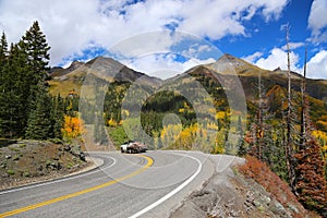 A flatbed pickup truck on mountain highway in Colorado Rocky Mountains during fall peak colors