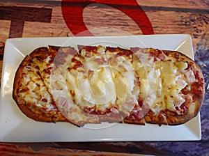 Flatbread hawaiian pizza on a rectangular plate