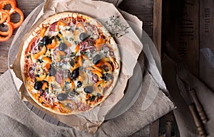 Flatbread pizza garnished with fresh arugula on wooden pizza board, top view. Dark stone background. Person picking slice of pizza