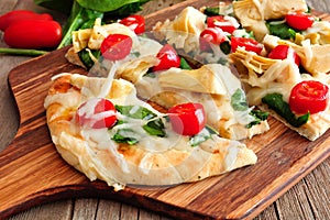 Flatbread pizza with mozzarella, tomatoes, spinach and artichokes, close up