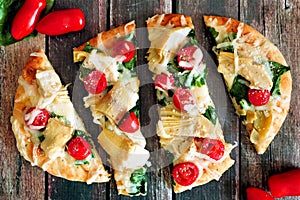 Flatbread pizza with mozzarella, tomatoes, spinach, artichokes, over rustic wood