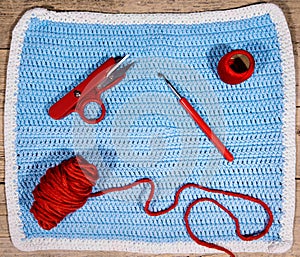 Flatlay, blue crocheted cloth and red utensils for handiwork hob