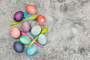 Flatlay, colorful dyed easter eggs and spoons on grey background, copyspace