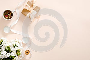 Flatlay composition with gift box, flowers bouquet, ribbon, candles, tea cup on pastel pink background. Flat lay, top view, copy