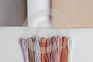 Flatlay creativity: canva aida beige, gray and white and multi-colored floss threa