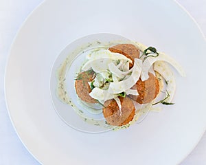 Flatlay of croquette on a white plate with fennel.