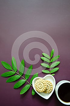 Flatlay A cup of coffee and two small round delicious cookies on a saucer in the shape of a heart beautiful rowan leaves