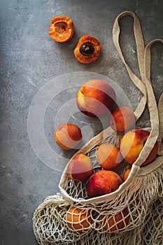 Flatlay with fresh ripen apricots in a market sack on a grey background