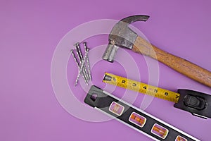 Flatlay of Hammer, Nails, Tape Measure and Level Isolated on a Lavender Purple Background