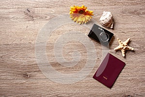 Flatlay holiday /travel theme with brown background with camera,passport,shell ,starfish and flowers.