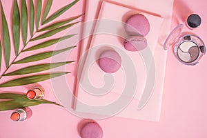 Flatlay of notebook, cake macaron, flower on pink table. Beautiful breakfast with macaroon
