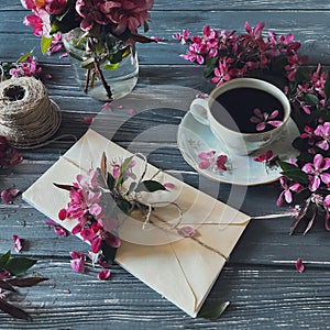 Flatlay with pink spring flowers, a cup of coffee, threads, an envelope. Top view.