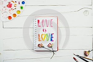 Flatlay of sketchbook with handlettering inscription `Love is love`