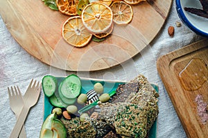 Flatlay of snack plate and boards with linen breads, fresh vegetables, dried fruits, fruit candies, nuts, olives, himalaya salt