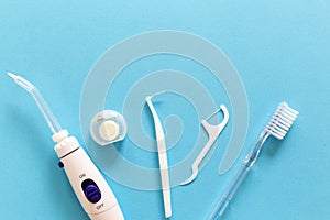 Flatlay of toothbrush, dental floss, irrigator and other hygiene tools on a blue background with copy space for your text.