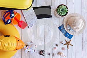 Flatlay Travel Top View. On white wooden background lie plane tickets, passports, map, seashells, yellow suitcase, inflatable