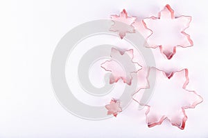 Flatlay with variety of snowflake copper cookie cutters on white sparkling background. Holiday, Christmas and New Year