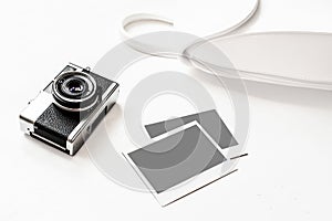 Flatlay vintage retro camera on wooden white background with empty instant paper photo placed your pictures. Top view