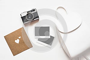 Flatlay vintage retro camera on wooden white background with empty instant paper photo placed your pictures. Top view