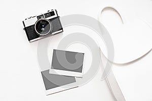 Flatlay vintage retro camera on wooden white background with empty instant paper photo placed your pictures. Top view