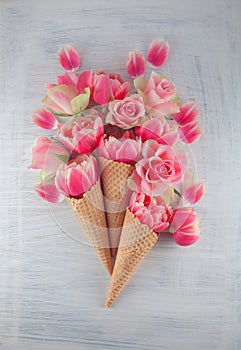 Flatlay waffle sweet ice cream cone with pink tulips blossom flowers over white wood background