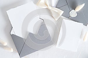 Flatlay wedding stationery set on white background. Open envelope with invitation card mockup, dried flowers top view