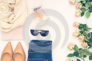 Flatlay of women`s stylish neutral outfit and roses on white bacground. Trendy clothes collage. Minimal and beauty blog