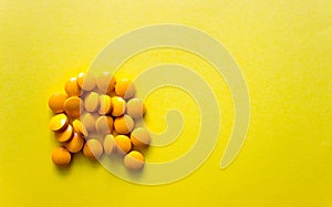 Flatlay yellow pillows of dietary supplements on yellow background. Free copy space. Concept of healthy life, vitamin