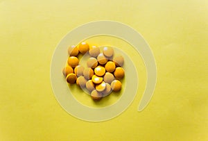 flatlay yellow pills of dietary supplements on yellow background. Free copy space. Concept of healthy life, vitamin
