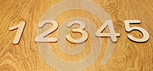 Flatley, side view of large wooden numbers one, two, three, four and five lying in order on a wooden background