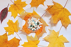 Flatley, yellow maple leaves on a white background, on a leaf in the middle are pills. Concept of increasing morbidity