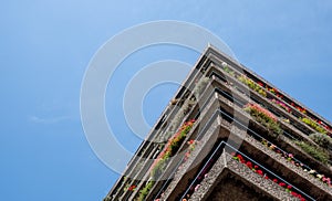 Flats built in post-war Brutalist style architecture at The Barbican in the City of London UK, with colourful flowers on the balco