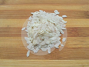 Flattened rice heap on wooden background