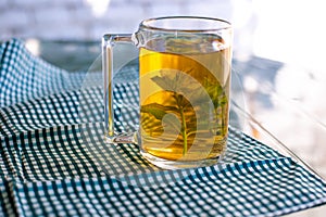 Flavored green tea with mint in a transparent mug. Open-air morning tea