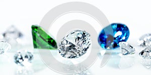 Flawless diamonds, blue sapphire and a green emerald in front of white background