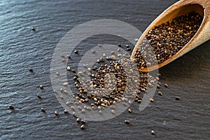 Flax chia seeds in wooden spoon on black food background. Pile superfood. Vitamin antioxidant breakfast or morning snack