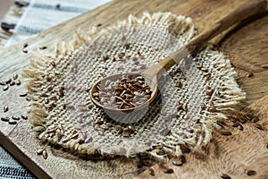 Flax seed inside wooden spoon on rustic table.