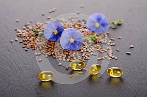 Flax seeds, beauty flower and oil in caps on a grey background