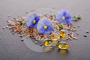 Flax seeds, beauty flower and oil in caps on a grey background