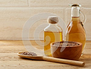 Flax seeds in bowl and flaxseed oil in glass bottle on wooden background, top view, close-up, selective focus