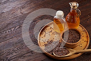 Flax seeds in bowl and flaxseed oil in glass bottle on wooden background, top view, close-up, selective focus