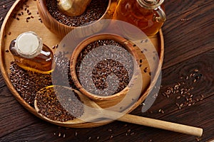 Flax seeds in bowl and flaxseed oil in glass bottle on wooden background, top view, close-up, selective focus